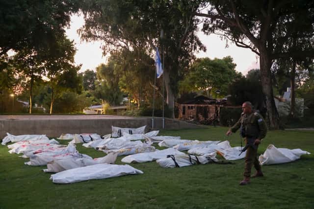 GRAPHIC CONTENT: A member of Israeli security walks past covered bodies of Israeli victims of the weekend’s infiltration by Palestinian militants at kibbutz Beeri near the border with Gaza on October 11, 2023. Credit: AFP via Getty Images