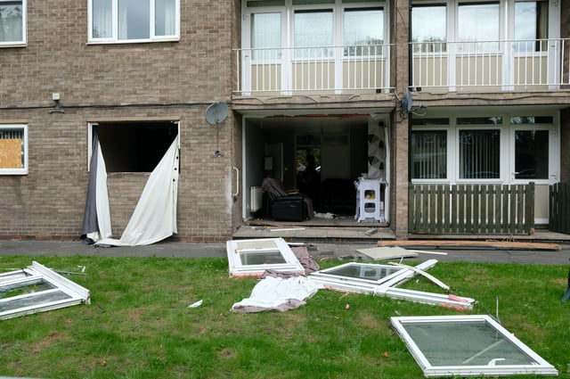 The interior of a maisonette is visible after its windows and door appear to have been blown out of their fittings.