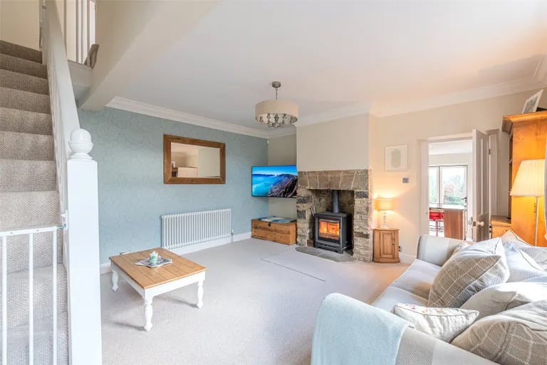 A spacious living room with a log burner and stairs to the first floor.