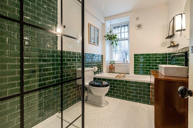 Stylish refitted four-piece bathroom comprising WC, wash hand basin with vanity storage, bath, and walk in shower with rainwater and handheld fittings. The bathroom is complete with partially tiled walls, and tiled floor coverings