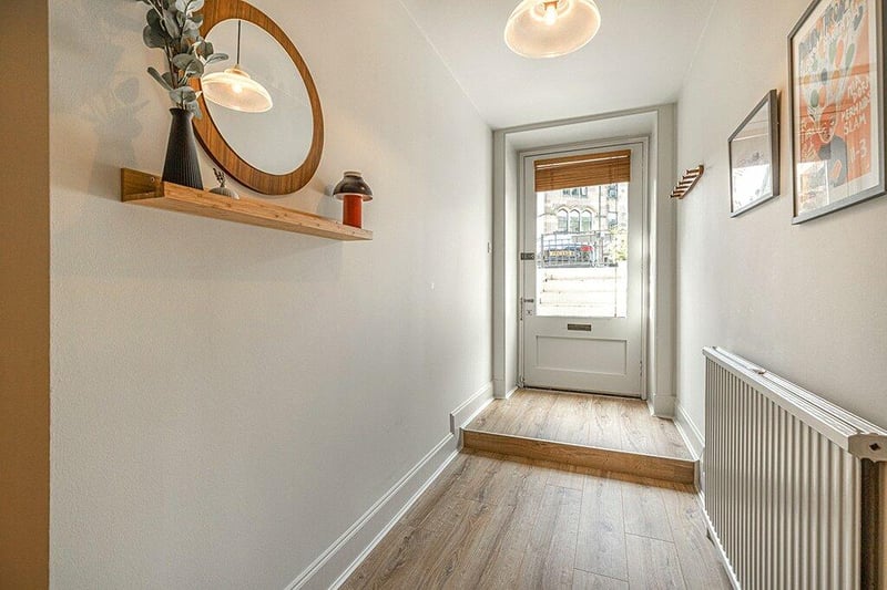A bright and welcoming reception hallway with fresh neutral decoration, broad plank oak effect laminate floor coverings.