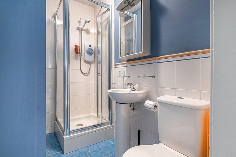 Shower room comprising WC, wash hand basin, shower with electric shower, partially tiled floor coverings and tiled flooring. 