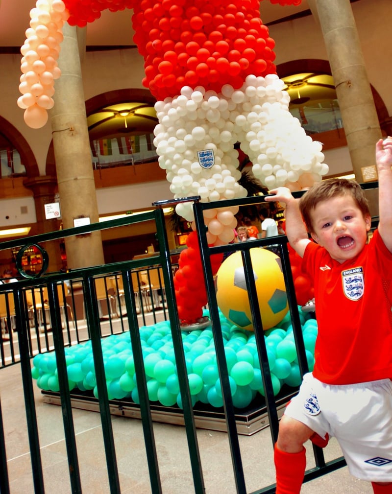 30-month-old Ben Thorpe cheers on his team at Meadowhall's Oasis dining quarter, alongside the giant England player made out of balloons