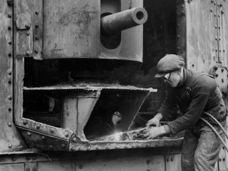 A World War I tank being broken up by a workman with an oxyacetylene torch at Barshaw Park in Paisley. World War 2 would break out just 2 years later.