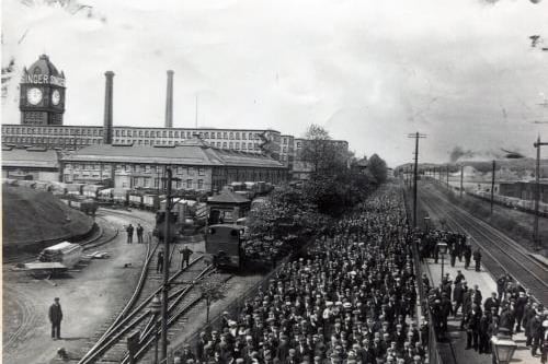 View of the factory from Kilbowie Road with the workforce coming out. Taken just after clock face changed in 1905/06 but before the railway was moved northwards in 1907.