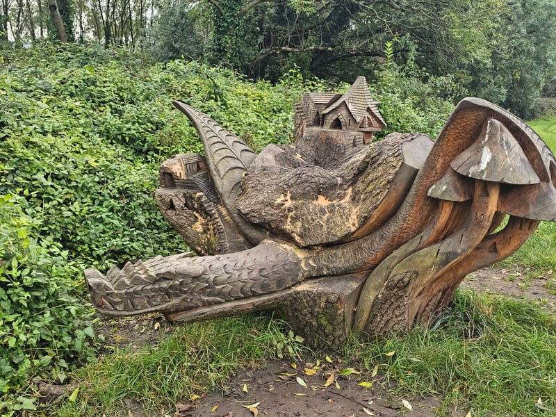 The Dragon Mushroom Castle sculpture is located near the entrance to Hermitage Wood and is trackable with Google Maps. The design features an intricate town atop mushrooms and resting on a dragon.
