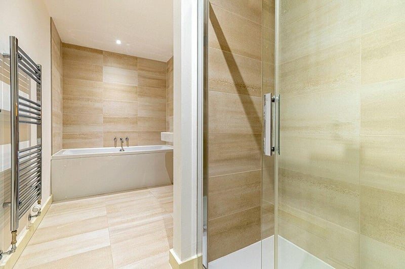 Spacious family bathroom complete with four piece suite comprising WC, wash hand basin, large tub, and shower complete with tiled floors, partially tiled wall and there is integrated storage and a heated towel rail. 