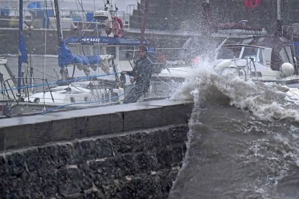 A boat owner braves the conditions inside the harbour to secure boats in Stonehaven on the east coast of Scotland on October 19, 2023, as wind and rain from Storm Babet cause travel chaos. 