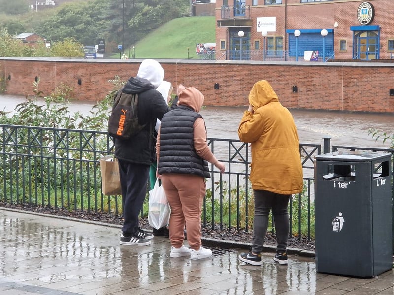 People look out over the River Don in Sheffield as the water level continues to rise during Storm Babet