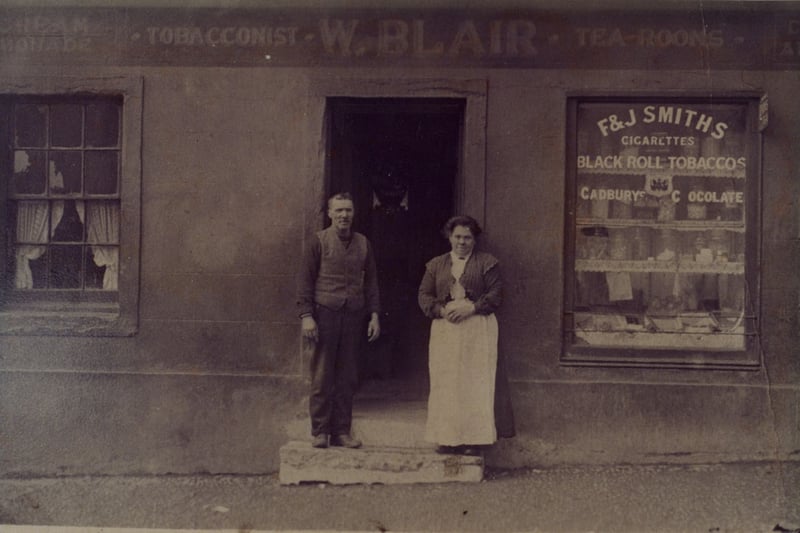 Mr and Mrs Blair are photographed at the door of their tobacconists’ shop and tea rooms at 37 Main Street, Cumbernauld village - take a look at the signage on the window and you can see you could grab some Cadbury’s chocolate alongside some black roll tobacco, we don’t know what sounds more delicious (definitely the chocolate).
