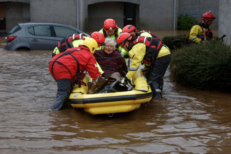 Members of the coastguard rescue a woman from flood waters surrounding the houses in Brechin.