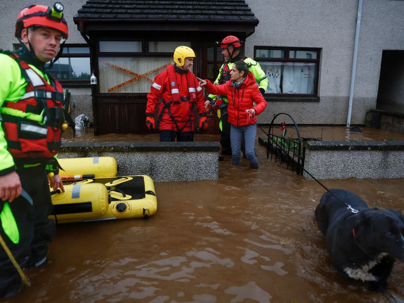 A dog leads its family out of their flooded house in Brechin.