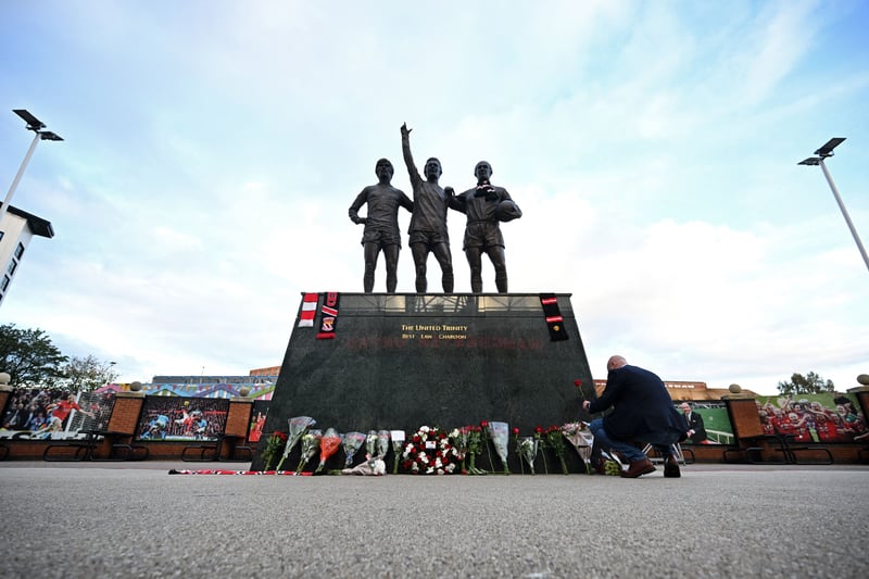 Tributes and flowers are pictured at the base of the 'United Trinity' sculpture, depicting former Manchester United players George Best, Denis Law and Bobby Charlton, , outside of Old Trafford Stadium in Manchester