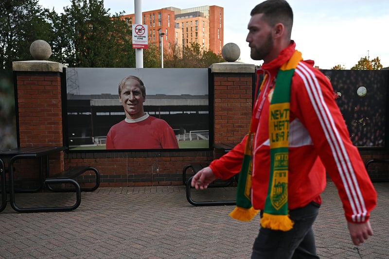 A pedestrian walks past an image of former Manchester United player Bobby Charlton outside of Old Trafford Stadium