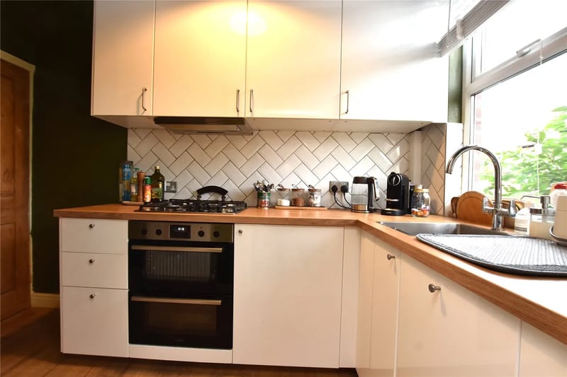 The fitted kitchen has modern white cabinets and tiling.