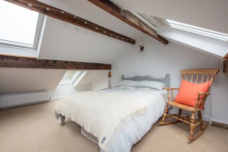 On the second floor is this large double bedroom with skylight windows and exposed wood ceiling beams.