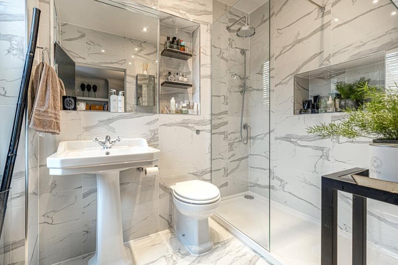 Inside the outstanding  re-fitted en suite shower room with three piece white suite and “Carrera” style marble tiling. 