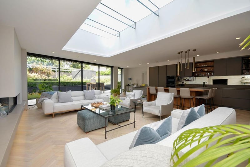 This open-plan living and kitchen area has built in panelled storage to one end and a recessed living flame gas fire to the other. It boasts maximum natural light through floor to ceiling sliding doors and a glazed roof section. 