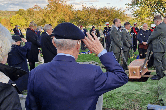 A veteran salutes as Cyril Elliott's coffin is lowered into the ground.