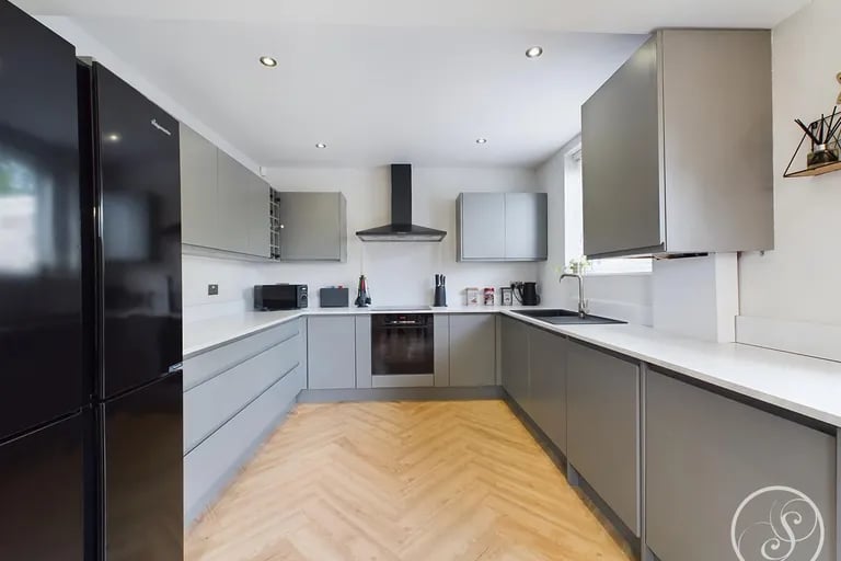 The modern kitchen has fitted base and wall units and integrated oven, hob with extractor, dishwasher and washing machine.