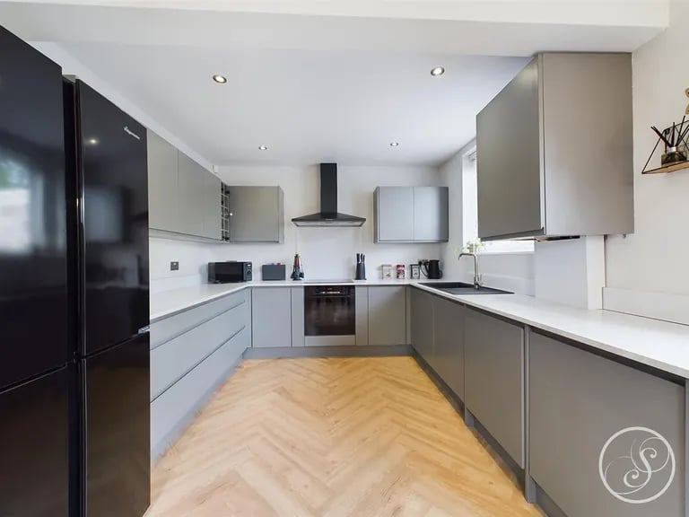 The modern kitchen has fitted base and wall units and integrated oven, hob with extractor, dishwasher and washing machine.