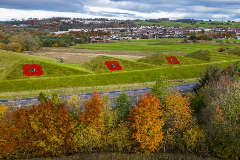 The 30ft-wide poppies are painted onto grass pyramids alongside the M8 motorway in West Lothian (SWNS)