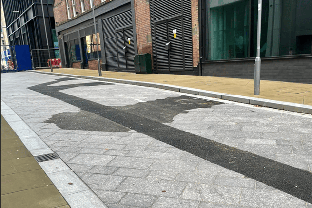 Asphalt cutting through granite pavement on Wellington Street.