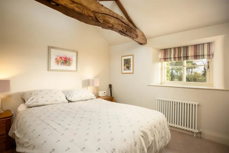 This stunning double bedroom has exposed wood beam.