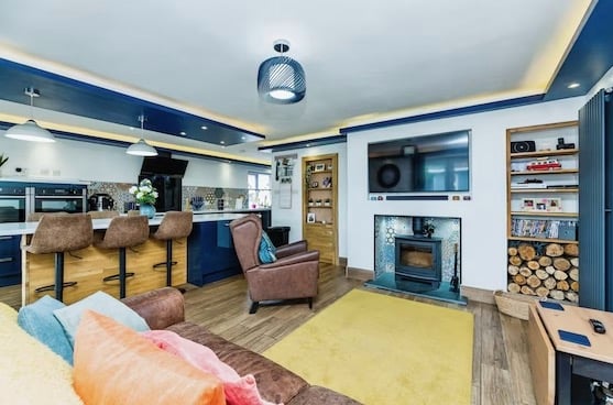 The other side of the kitchen-diner reveals a homely living space with armchairs and woodburner. Purplebricks