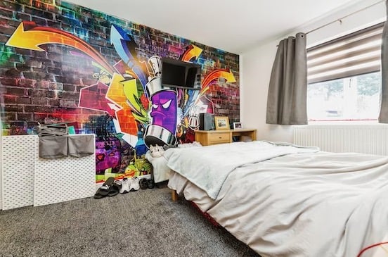 This bedroom has a unique and colourful mural as well as a television on the wall. Pic: Purplebricks