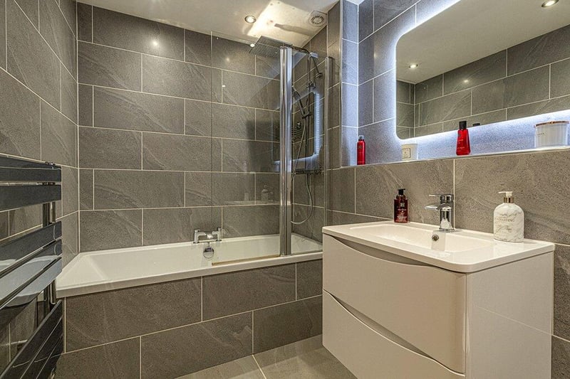 The impressive, fully re-fitted contemporary bathroom with three-piece white suite and mixer shower over the bath.