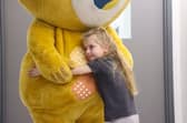 A young girl hugs Theo the bear after a scan at Sheffield Children's Hospital