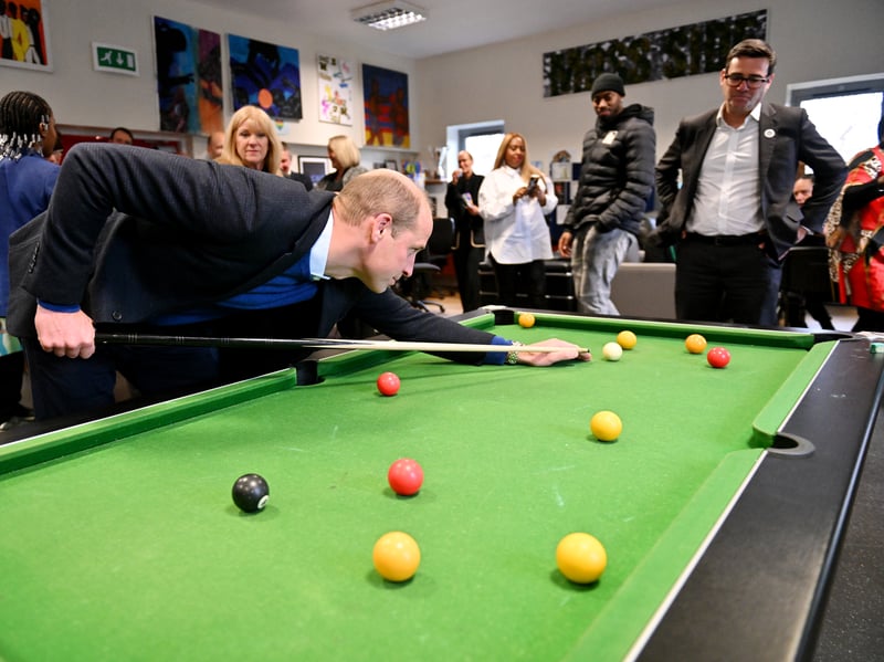 Andy Burnham looks on as Prince William plays pool at the Hideaway Youth Project 