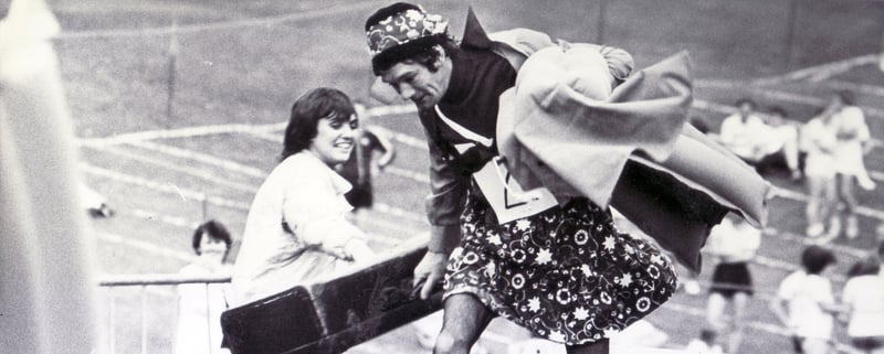 Pictured during the Great Sheffield Race in Norfolk Park, Sheffield, in aid of the Northern General Hospital Baby Care United Appeal Fund, is one of the male competitors dressed in ladies clothes with case and lilo crossing one of the obstacles in August 1982