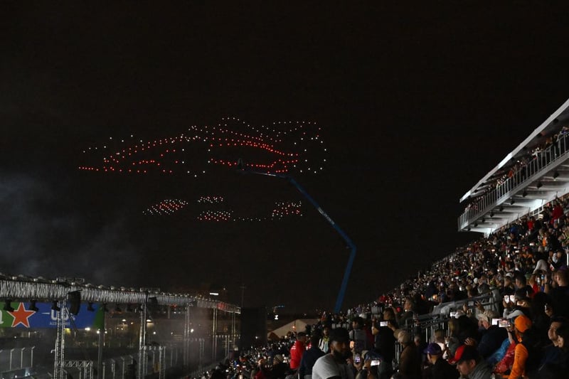 Drones perform a light show revealing an F1 car as fans gaze on at the Opening Ceremony.