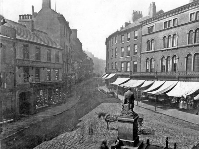 The Ebenezer Elliott monument, on Market Place, Sheffield, looking towards High Street, sometime between 1851 and 1899. The shops on the right include Thos. Myers jeweller, Alfred Brookes hosier and glover, and Robert Wm. Brookes restaurant, with the George Hotel on the left