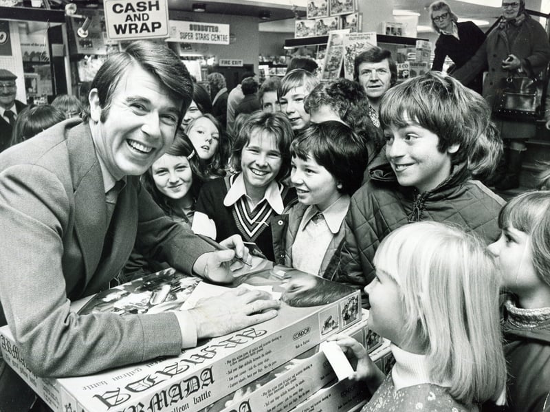 Television presenter Leslie Crowther pictured at Redgates toy store, Sheffield, surrounded by a crowd of smiling youngsters, in November 1975