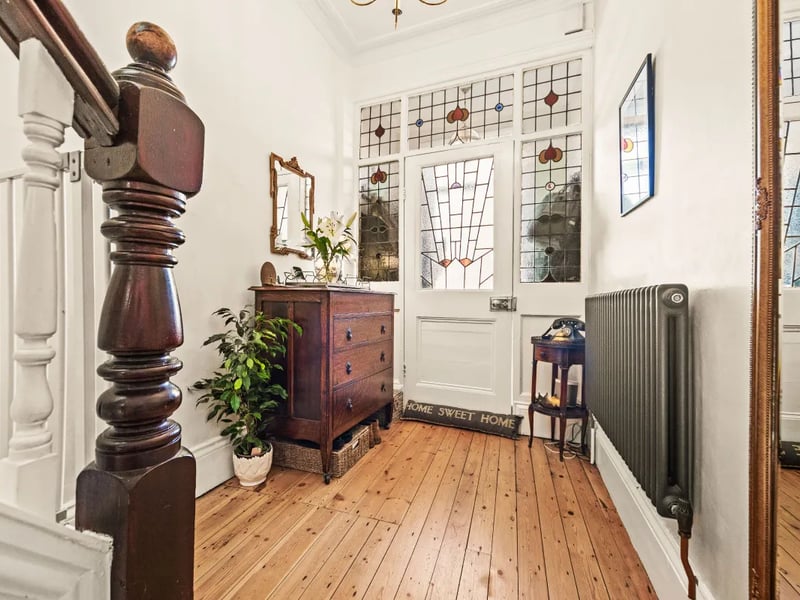 The hallway with period glazed door, wood floors and high ceilings.