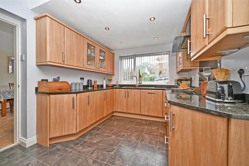 The modern kitchen with wooden finish has a range of appliances and units.