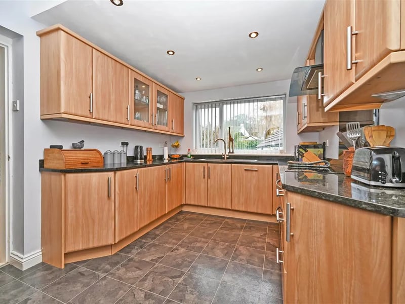 The modern kitchen with wooden finish has a range of appliances and units.