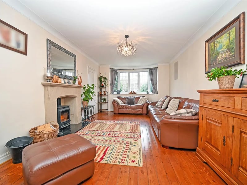The spacious living room has a fireplace and stripped wooden floors.