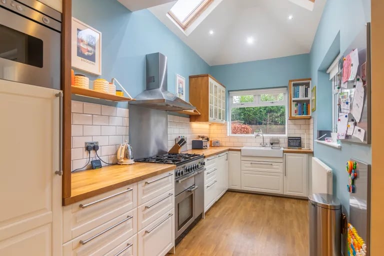 The modern fitted kitchen has double ovens, wooden worktops and Velux skylights.