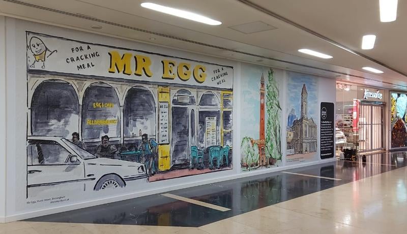 Birmingham New Street is home to some amazing street art by talented Birmingham artist Stacey Barnfield whose iconic Colour Pallette Company and Draw My City brand has created designs for cities and towns across the UK and Ireland. In Grand Central, above New Street, you can see his Birmingham Colour Pallette along with paintings of iconic Brummie landmarks past and present, including Mr Egg.