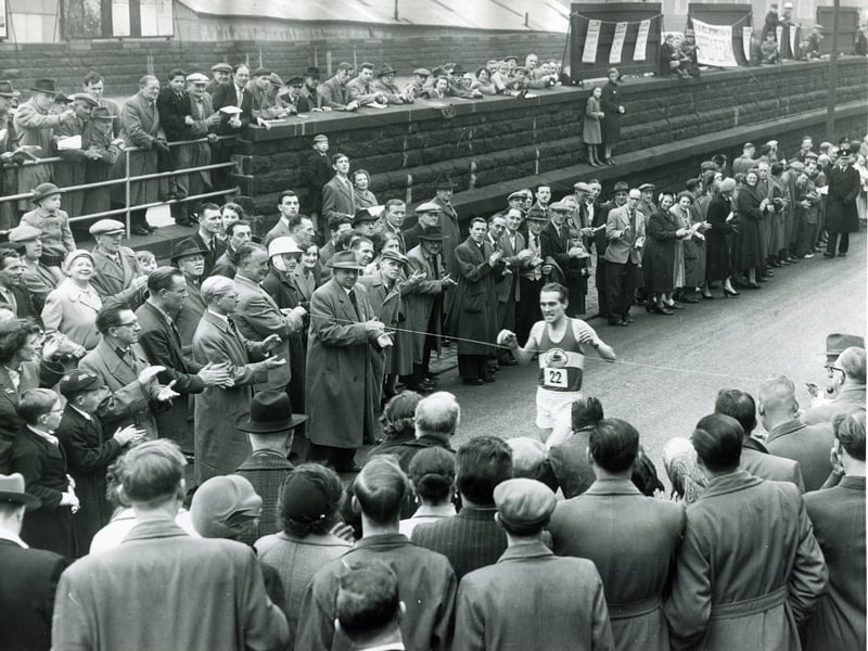 Amidst cheering crowds, A P Keily comes in to win the Sheffield Telegraph's 12th annual Easter Marathon from Doncaster to Sheffield, on April 22, 1957