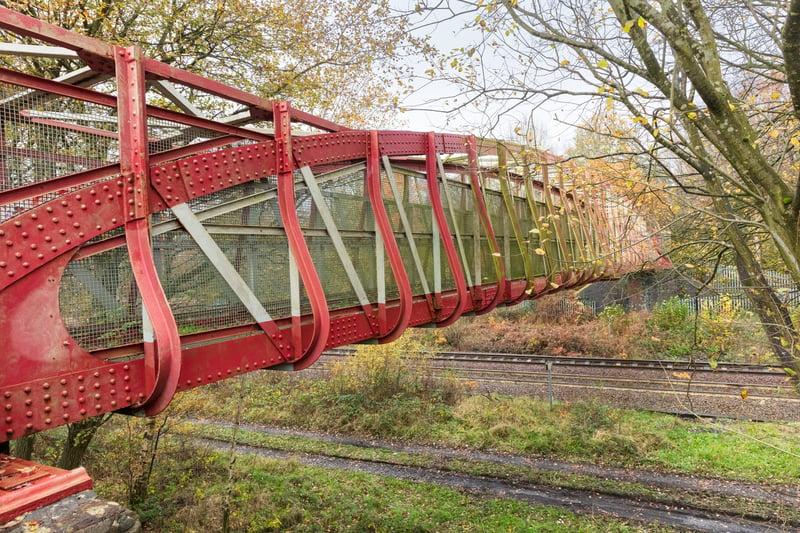 This unusually long, single-span, wrought-iron pedestrian railway footbridge dates from 1887. It was built during the peak period of railway bridge construction and spanned nine tracks, with an unusual large ramp on the south side rather than steps leading up to it. It has survived with very little alteration and its architectural interest lies in its elegant design.