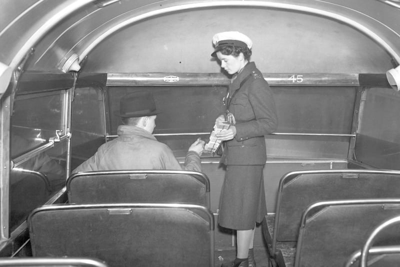 A bus conductress collecting fares from a passenger in Sunderland at Christmas in 1940.