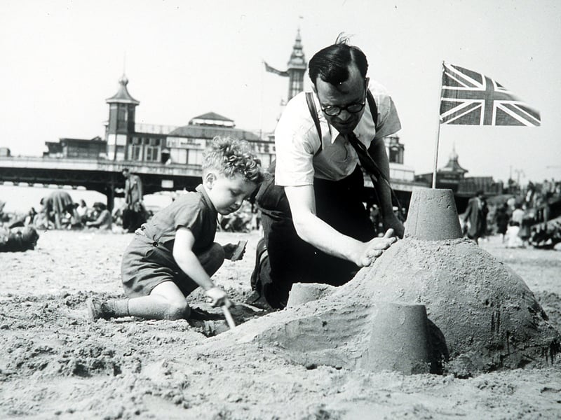 Building sandcastles on Blackpool beach with Central Pier in the background, 1947