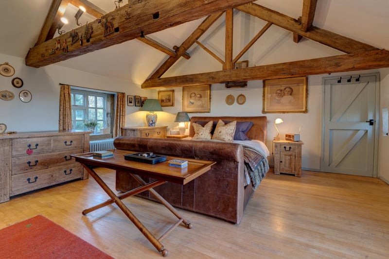 Heading upstairs, an “exceptionally spacious” master bedroom includes an impressive vaulted ceiling and exposed wooden beams. It has side-facing hardwood windows, feature spotlights on the beams and timber flooring. To one wall, there is a range of fitted furniture that incorporates long hanging.