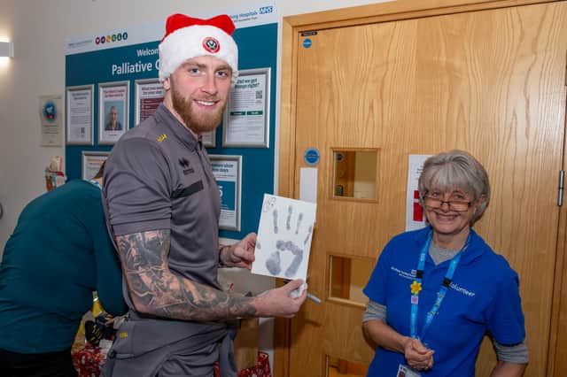 Oli McBurnie, with a handprint which will be used to create a piece of artwork for the ward, and Sheffield Teaching Hospitals volunteer