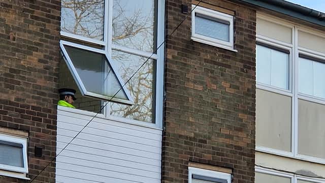 A police officer can be seen through the window of the flat block on Ironside Walk, Sheffield. It is believed the man was found dead in one of the properties.